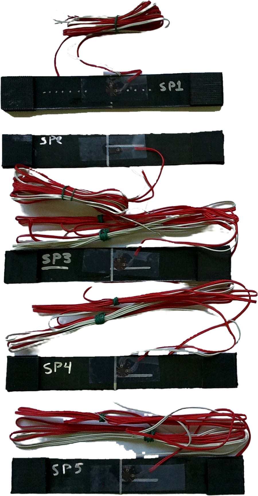 Composite tensile coupons SP1 to SP5 with tabs and bonded piezoelectric sensors, tested in tension perpendicular to the fibers